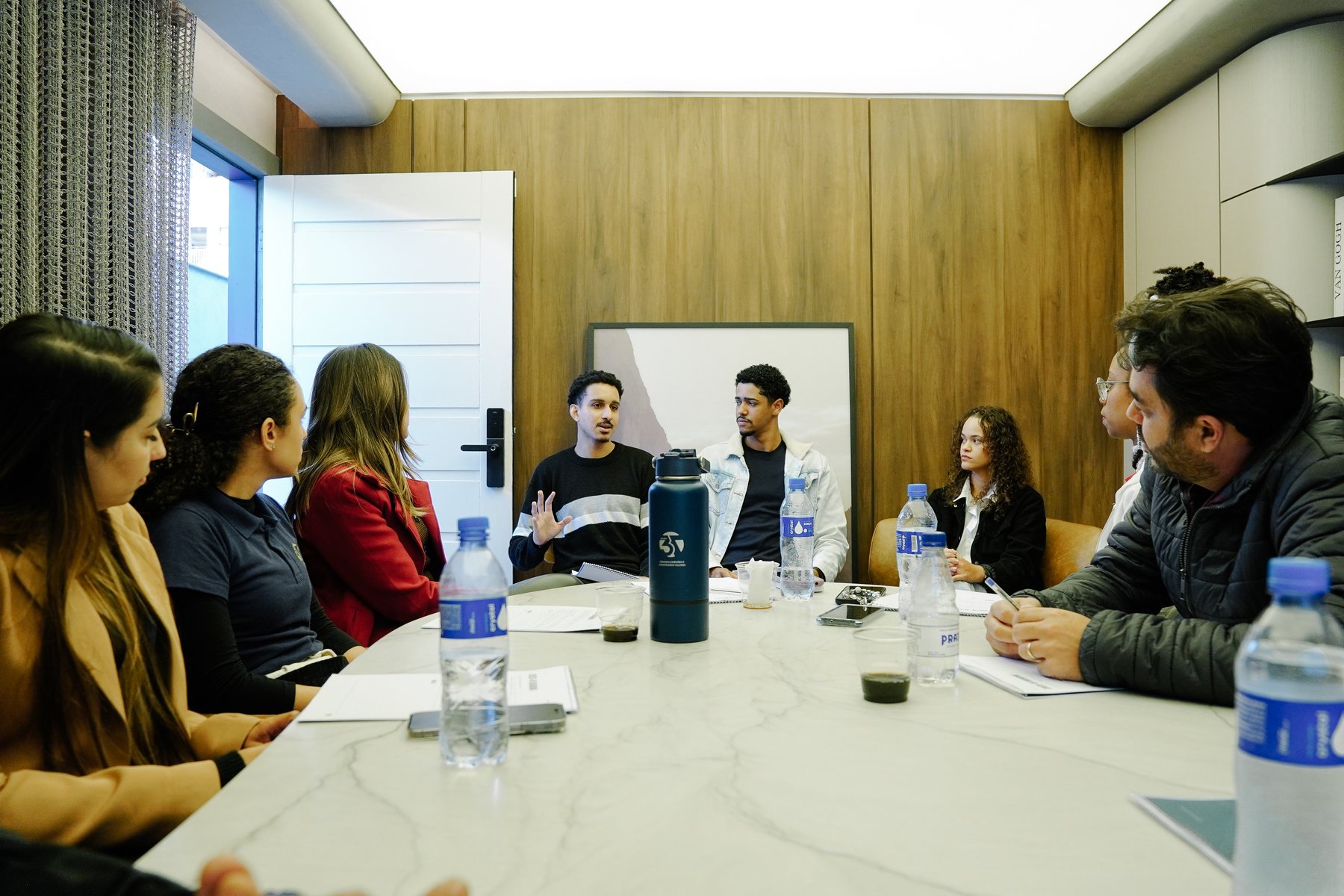 Participantes em roda na mesa de reunião conversando durante o workshop.
