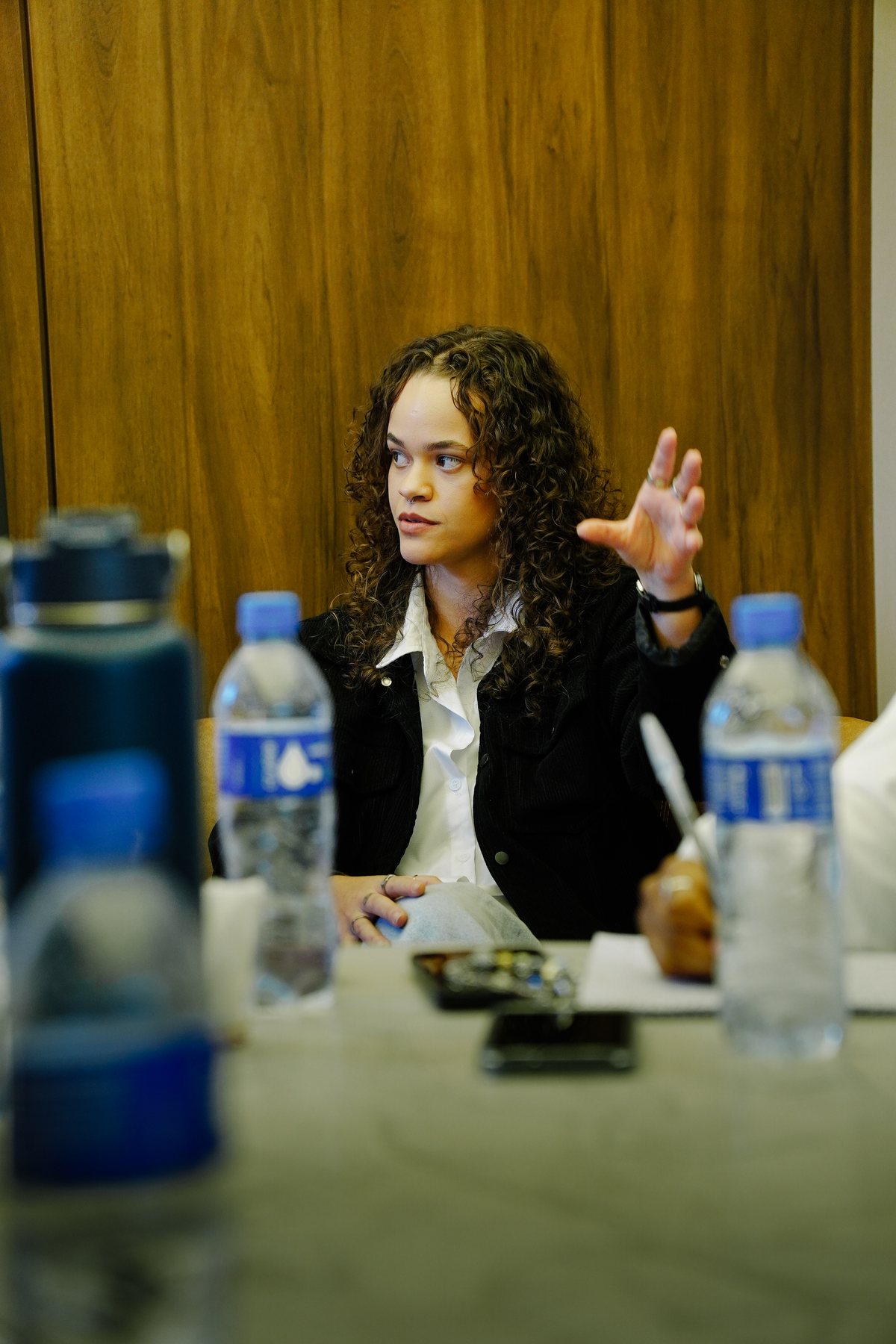 Facilitadora gesticulando enquanto conduz o workshop, com garrafas de água em primeiro plano.